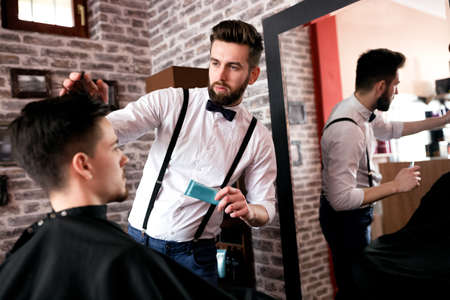 Hairdresser adjusts hair a customer with a gel in barbershop salonの写真素材