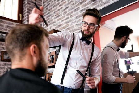 Hairdresser adjusts hair a customer with a comb in barbershop salon