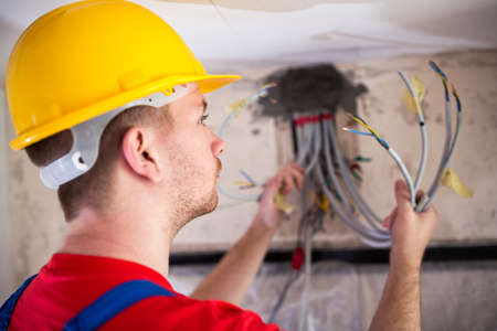 Electrician inspecting cables and wires in order to connect them on a distribution boardの写真素材