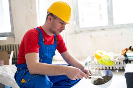 Manual making of gypsum mixture for filling of wall hollows