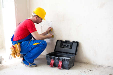 Electrician checking the voltage level in wall socket cables