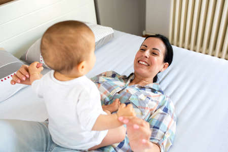 Young mother enjoying time and relaxing through playing with her infant