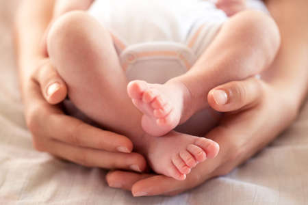 Tender touch of a caring mother holding her child kindly and gently on the bed