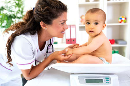 Just a cute baby sitting upright  on the weight measuring deviceの写真素材