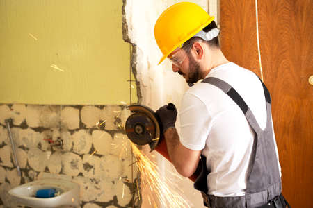 Crafty worker cutting metal fittings from the concrete wall using grinder