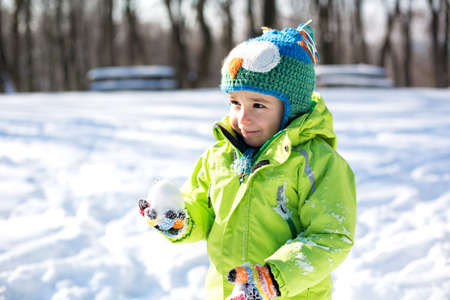 Little boy enjoying his time in the snow curiously looking and exploring aroundの写真素材