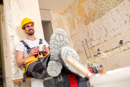 Smiling young worker enjoying his break time with a cup of coffee