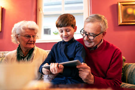 Grandson teaching his grandparents how to use a tablet and search the internet