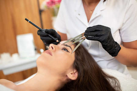 Cosmetic tattoo specialist using state of the art hand tools for enhancing eyebrows appearanceの写真素材