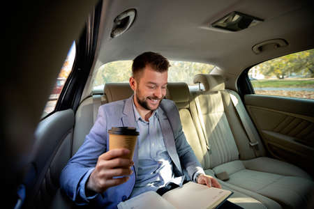 Businessman drinking coffee and studying some notes from the previous meeting