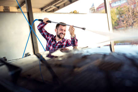 Charming young man paying attention to every detail as he washes his automobileの写真素材