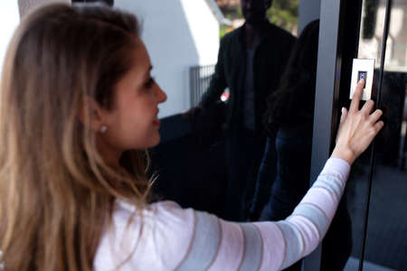 Woman pressing the ringing bell button on the entrance door