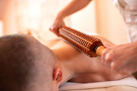 Young man having a neck massage with a wooden roller