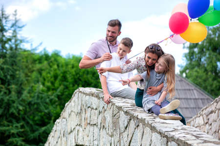 Family members bent on the side of the stone bridge smiling and having a good timeの写真素材