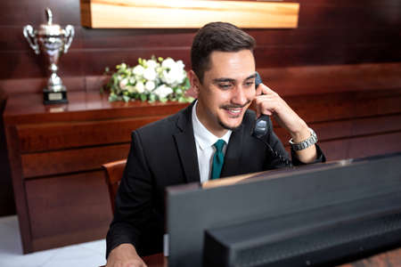 Smiling receptionist tending to hotel needs, hotel service conceptの写真素材