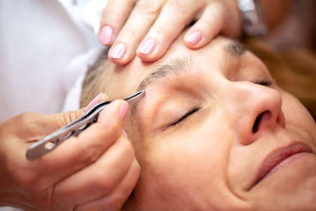 Middle aged woman getting an eyebrow treatment in a beauty salonの写真素材