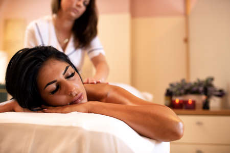 Beautiful dark tanned woman in a massage studio, beauty concept