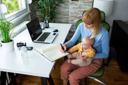Mommy and baby working together, working from home and parenting conceptの写真素材