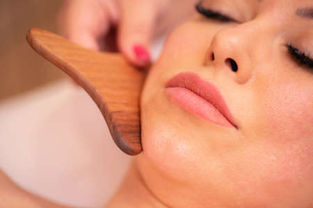 Facial madero massage of a neck and chin area with natural fragrant wood massagerの写真素材