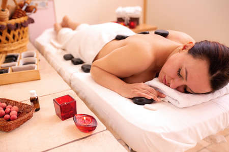 Mature woman in spa having a healing volcanic stone therapy, black basalt stone conceptの写真素材