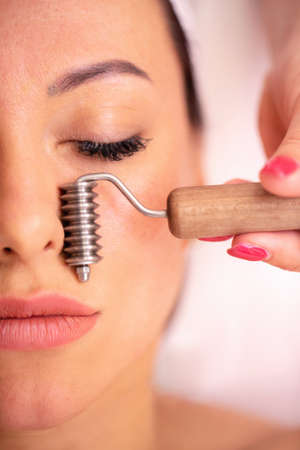 Woman getting a facial madero massage with a face roller in a beauty centerの写真素材