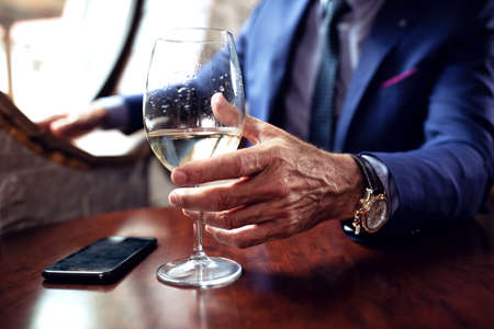 Close up of a wine glass held by a businessmanの写真素材