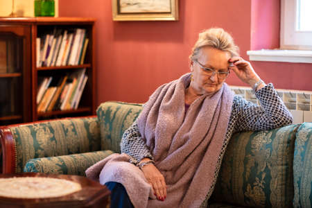 Lonely elder woman sitting on the couch, retirement home