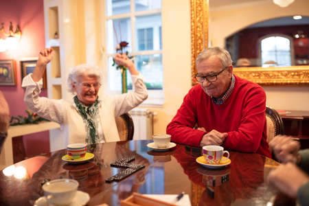 Older woman celebrating a win in a game dominos, quiet evening timeの写真素材