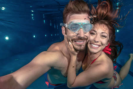 Two people expressing love while diving in the swimming poolの写真素材