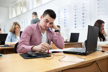 Young man sitting in the class studying his notes, student concept