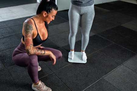 Weight measuring in the gym, coach and traineeの写真素材