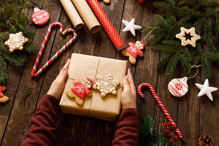 Wrapped present, winter holiday cookies and biscuits in various festive shapes, wooden background, merry Christmas and happy New Year conceptの写真素材
