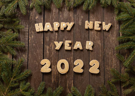 Home baked Christmas cookies in festive shapes wishing you a Happy New Year 2022, rustic wooden background with conifer branches concept, winter holidaysの写真素材