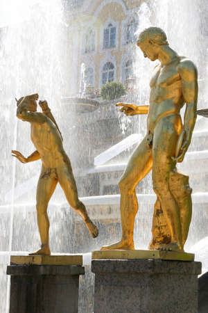 Two golden figures in front of fountain in russian summerpalaceの写真素材
