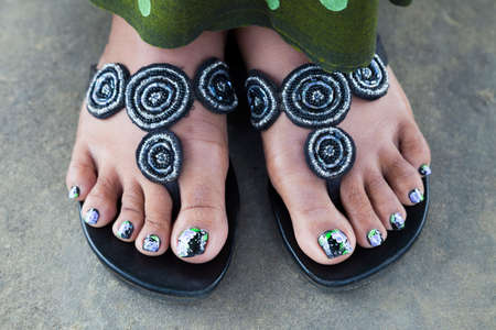 black green violet painted toenails of women feet in flip flops の写真素材