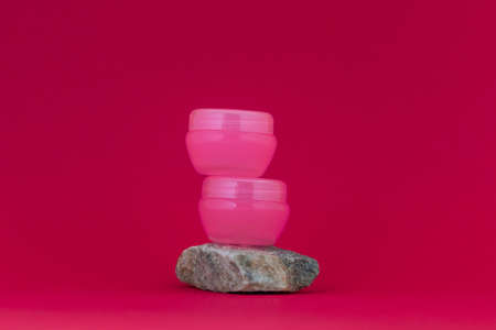 Three bottles for cosmetic products with white caps on a pink backgroundの写真素材