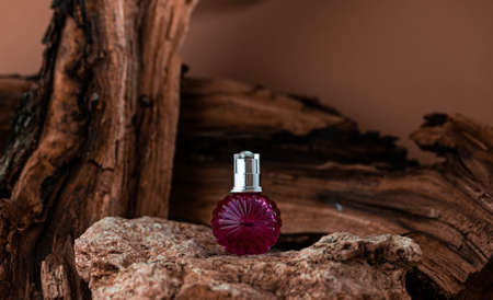pink glass cosmetic bottle on wood background stands on stone