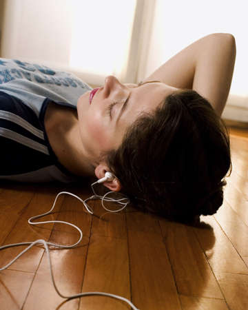 Girl laying down and listening to music via headset