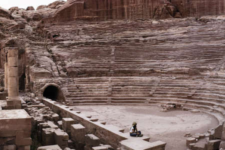 girl looking up to an ancient theatreの写真素材