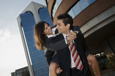 businesswoman riding piggyback on his colleague during a break from workの写真素材