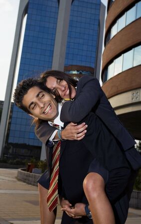 businesswoman riding piggyback on his colleague during a break from workの写真素材