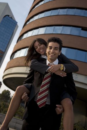 businesswoman riding piggyback on his colleague during a break from workの写真素材