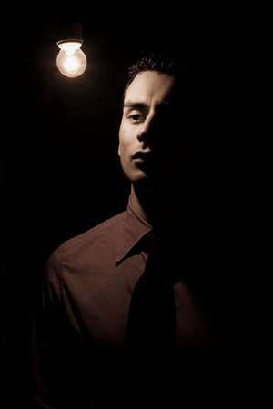 a young actor dressed as a businessman taking a pose in stage lighting