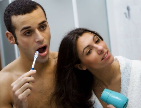 morning routine: the guy brushing his teeth and the girl hairdryingの写真素材