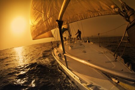 people on a sail boat at the sunsetの写真素材