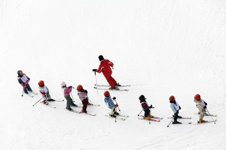winter scene: kids learning to ski and their instructorの写真素材