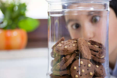 little boy looking at cookies in a jarの写真素材