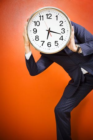 Businessman with clock on head, studio shot.の写真素材