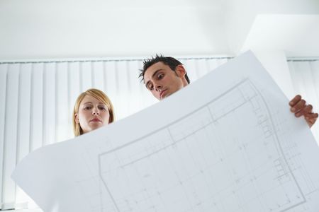 two architects examining blueprint indoors. Low angle view. Copy spaceの写真素材