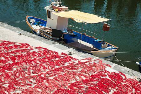 fishing boat anchored in wharf and red fishing netの写真素材